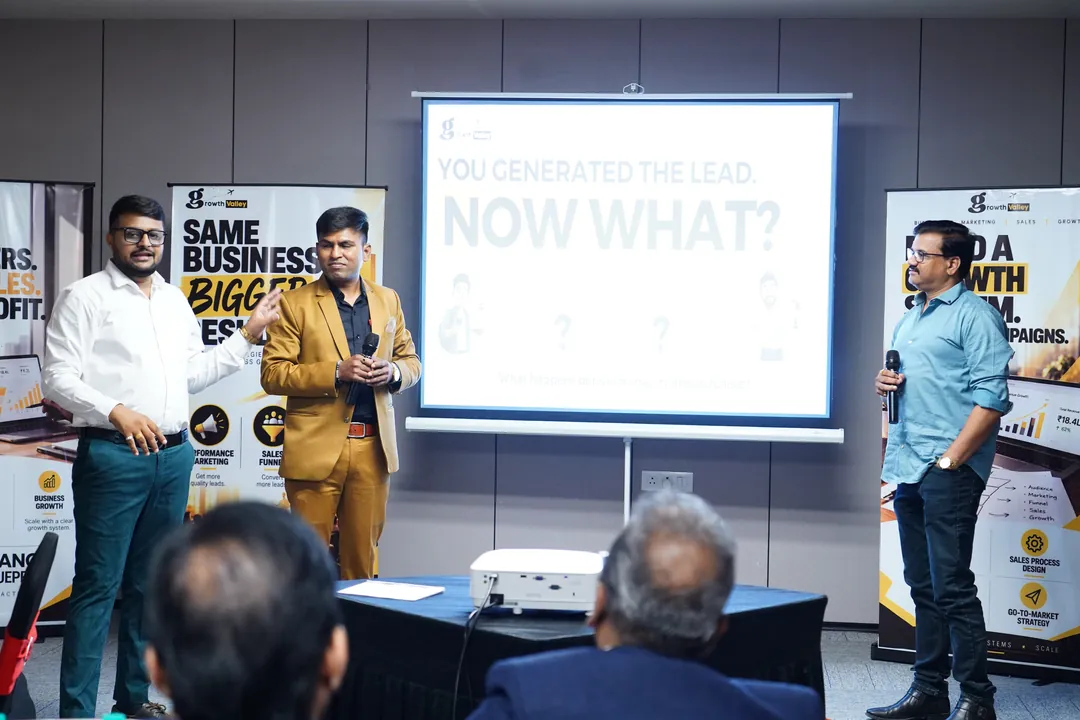 Umesh Khivasara presenting on stage with two co-presenters at a Growth Valley session